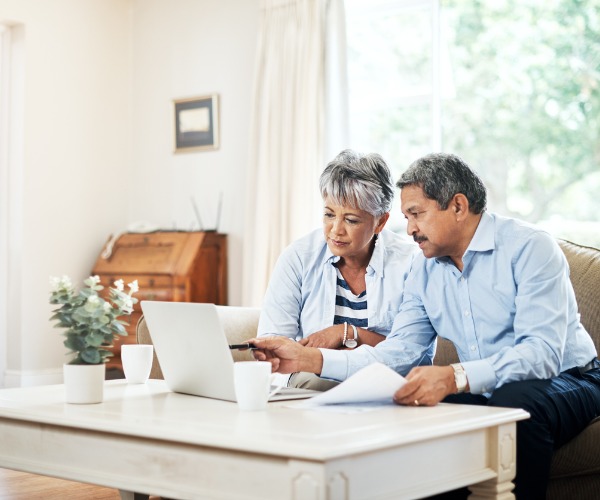 couple at home on couch with laptop on coffee table discussing retirement