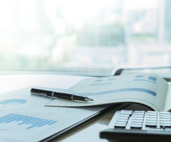 calculator on desk with pen resting on tax documents